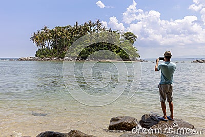 Tourist man standing on the stone in summer season and take a photo beautiful small island in phuket thailand Editorial Stock Photo