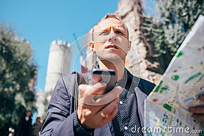 Tourist man try navigate himself with map and smartphone in unknown city Stock Photo