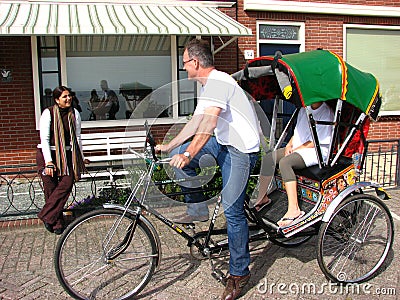 Tourist negotiating price on bike taxi, Volendam Editorial Stock Photo