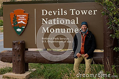 A tourist next the sign of Devils Tower National Monument in Wyoming Editorial Stock Photo