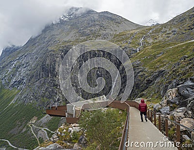 Tourist people at view point platform on Trollstigen or Trolls Path with green valley and waterfall at massif Trolltindene in Editorial Stock Photo