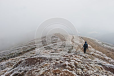 Tourist photographer with tripod on hand walking on frozen hill Stock Photo