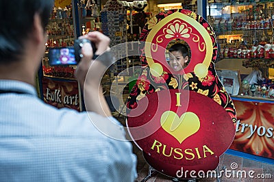 A tourist photographs a child, a Russian doll with the inscription I love heart Russia in the seaport on the background of a Editorial Stock Photo