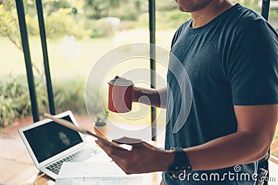 Tourist planning vacation hold cup of coffee and see tablet screen and trvel accessories around on the table. Vocation, travel, Stock Photo