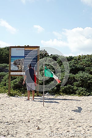 Tourist reading a sign on the beach in Cozumel Editorial Stock Photo