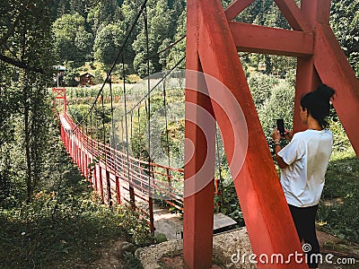 Tourist by red old metal structure with wooden pathway bridge in nature in Georgia countryside. Adjara hidden gems Stock Photo