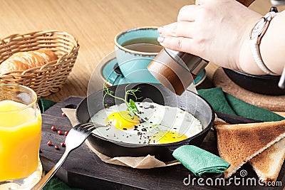 Tourist`s english Breakfast in cooking pan with fried eggs, sausages, bacon, toasts and coffee Stock Photo