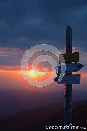 Tourist signpost on a mountain road at sunset Stock Photo