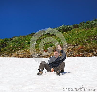 Tourist sliding on the snowfield in summer. Stock Photo