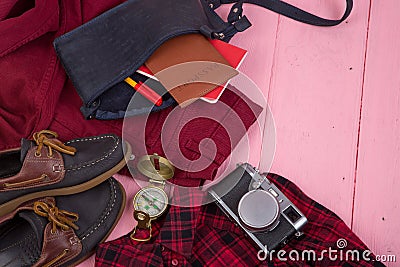 Tourist stuff - bag, jeans, passport, camera, compass, shoes, shirt, notepad on pink wooden background Stock Photo
