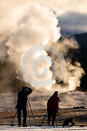 Tourist taking the explosion of old Faithful, Yellowstone in morning Stock Photo