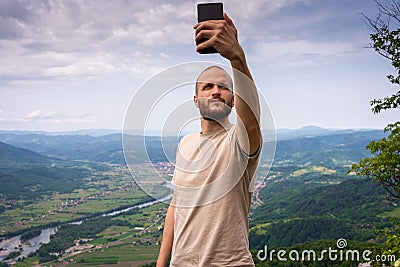 A tourist taking photo of himself while standing on top of the mountain Stock Photo