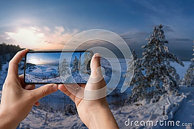 Tourist taking photo of snowy beach with dunes and Baltic sea coast surrounded by pine nd fir trees forest in Baltics Stock Photo