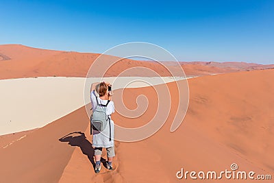 Tourist taking photo at Sossusvlei, Namibia. Scenic sand dunes, Namib desert, Namib Naukluft National Park, travel adventure in Af Stock Photo