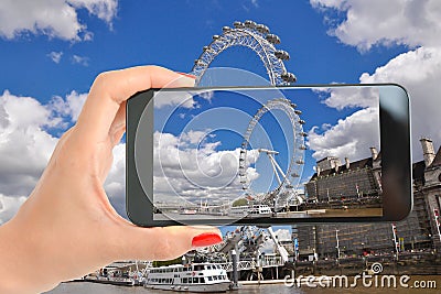 Tourist taking a photography with smartphone to London Eye on the banks of Thames River Editorial Stock Photo