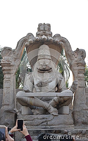 tourist taking photos of hypnotising stone carved statute of the Hindu god Vishnu in his Narsimha avatar, that is half lion Editorial Stock Photo