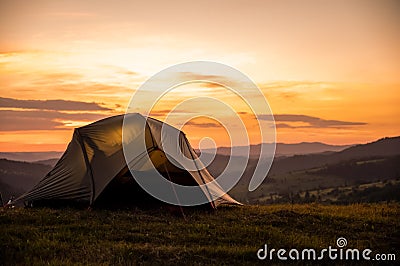 Tourist tent in the mountains under dramatic evening sky. Colorfull sunset in mountains. Camping travell concept. Traveler people Stock Photo