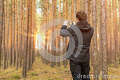 Tourist traveler taking pictures of sunrise in forest. Stock Photo