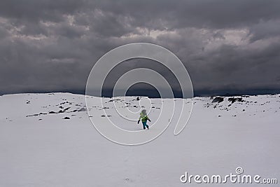 Tourist walking on a snowy plain against strong wind Editorial Stock Photo