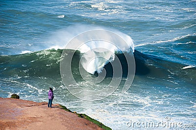 Tourist watching big waves in Nazare, Portugal Editorial Stock Photo