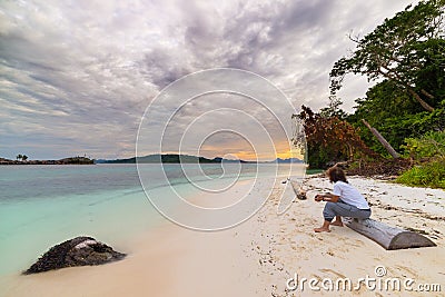 Tourist watching a relaxing sunset sitting on the beach in the remote Togean Islands, Central Sulawesi, Indonesia, upgrowing trave Stock Photo