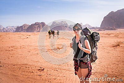 Tourist woman with friends in a desert. Jordan natural park Wadi Rum. Backpacker on the road. Woman hiker with backpack Stock Photo