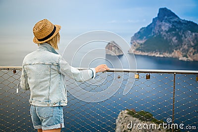 Tourist woman in jeans outfit and a straw hat looking at the Cap de Formentor Stock Photo