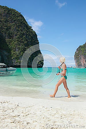 A tourist woman wearing green bikini walking on beautiful beach, Phi Phi island (Ko Phi Phi Ley), Krabi Province of Thailand. Editorial Stock Photo