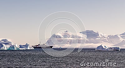 Touristic cruise liner among blue icebergs close to Cuverville Island Stock Photo