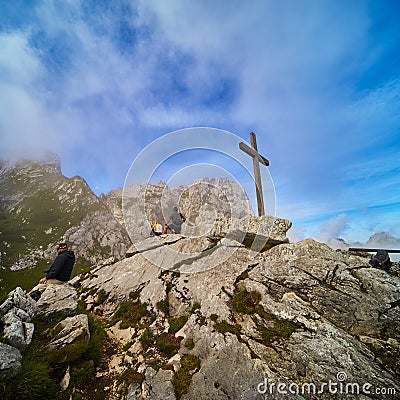 Tourists admire the Alpspitze mountains in Werdenfelser Land next to a simple wooden puritanical cross Editorial Stock Photo