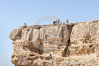 Tourists climb down the ropes from the cliff where the city of Mitzpe Ramon is located in the Judean Desert in Israel Stock Photo