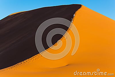 Tourists climb to the top of the dune Stock Photo