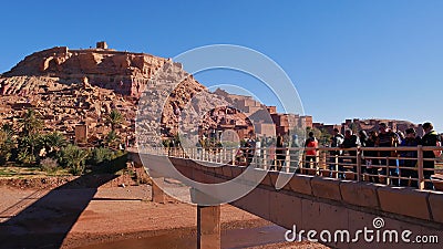 Tourists crossing a bridge on the way to the entrance of popular historic Moorish ksar and UNESCO world heritage. Editorial Stock Photo