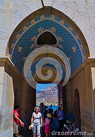 Tourists entering arch gate with colorful paintings at Panormitis Monastery. Editorial Stock Photo