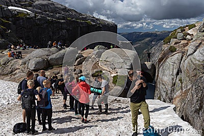 Tourists at the famous boulder Kjeragbolten that is wedged in a mountain crevasse, Norway Editorial Stock Photo
