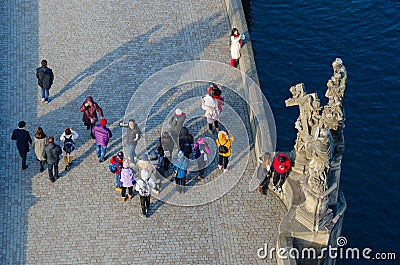 Tourists are on famous medieval Charles Bridge near sculptural composition Madonna and St. Bernard, aerial view, Prague Editorial Stock Photo