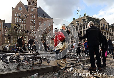 Tourists feed the pigeons in Amsterdam, Holland Editorial Stock Photo
