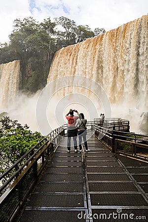 Tourists in the footbridge at iguazu falls veiw from argentina Editorial Stock Photo