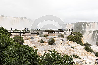 Tourists in the footbridge at iguazu falls veiw from brazil Stock Photo