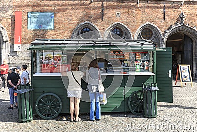 Tourists in front of a stand selling french fries in the market square in the center of Bruges, a beautiful medieval town in Belgi Editorial Stock Photo