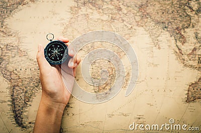 Tourists hold a compass and locate a place on a world map. Stock Photo