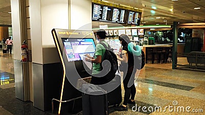 Tourists looking at screens in airport Editorial Stock Photo