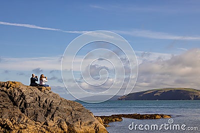 Tourists photographing the view with their phones on Cwm-yr-Eglwys beach. Wales, UK Editorial Stock Photo