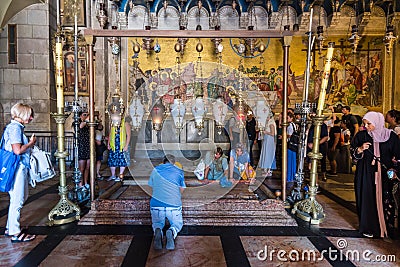 Tourists and pilgrims are playing Stone of Anointing or Stone of Unction, the spot where Jesus' body was prepared for burial by Editorial Stock Photo