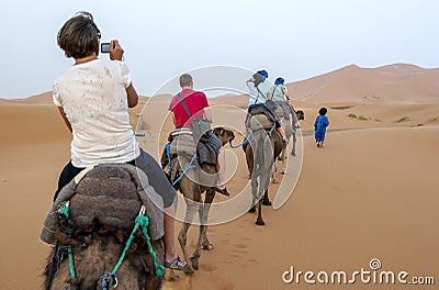 Tourists ride camels into Erg Chebbi at Merzouga in Morocco. Editorial Stock Photo