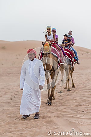 Tourists Riding Camel with Tamer in The Desert of Dubai Editorial Stock Photo