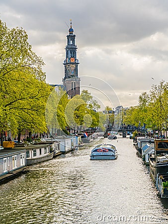 Tourists sailing in a canal boat on the Prinsengracht passing the Westertoren Editorial Stock Photo