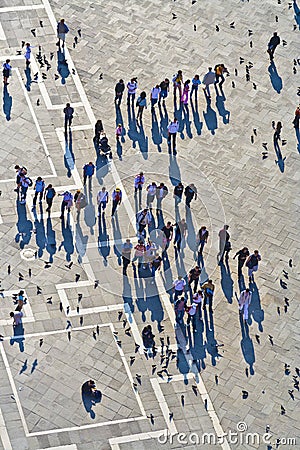 Tourists on San Marco square feed large flock of pigeons. San Marco square is the largest and most famous square in Venice Editorial Stock Photo