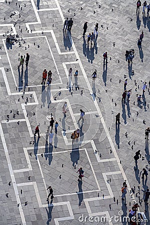 Tourists on San Marco square feed large flock of pigeons. San Marco square is the largest and most famous square in Venice Editorial Stock Photo