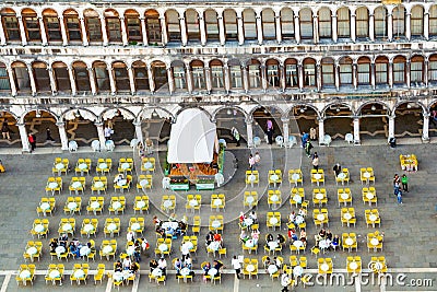 Tourists on San Marco square feed large flock of pigeons. San Marco square is the largest and most famous square in Venice Editorial Stock Photo